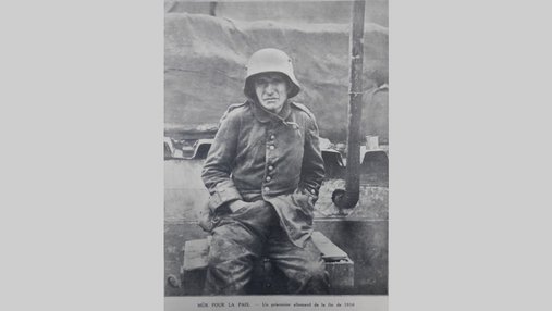 Photo d'un prisonnier allemand en uniforme assis sur une caisse de bois.