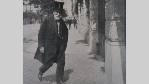 Photo de Paolo Boselli marchant dans la rue en costume et haut de forme