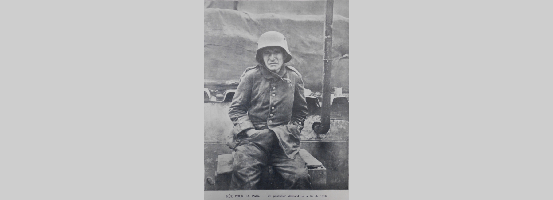 Photo d'un prisonnier allemand en uniforme assis sur une caisse de bois.